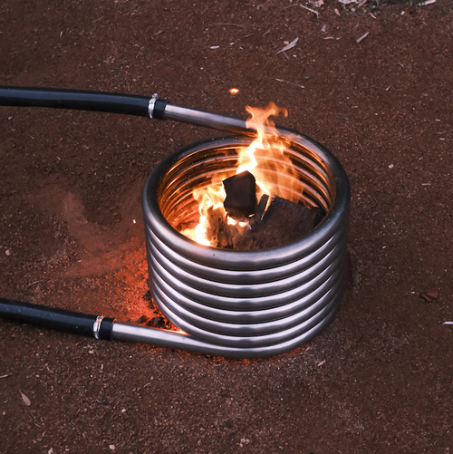 Wood fire coil kit burning beside a stock tank hot tub